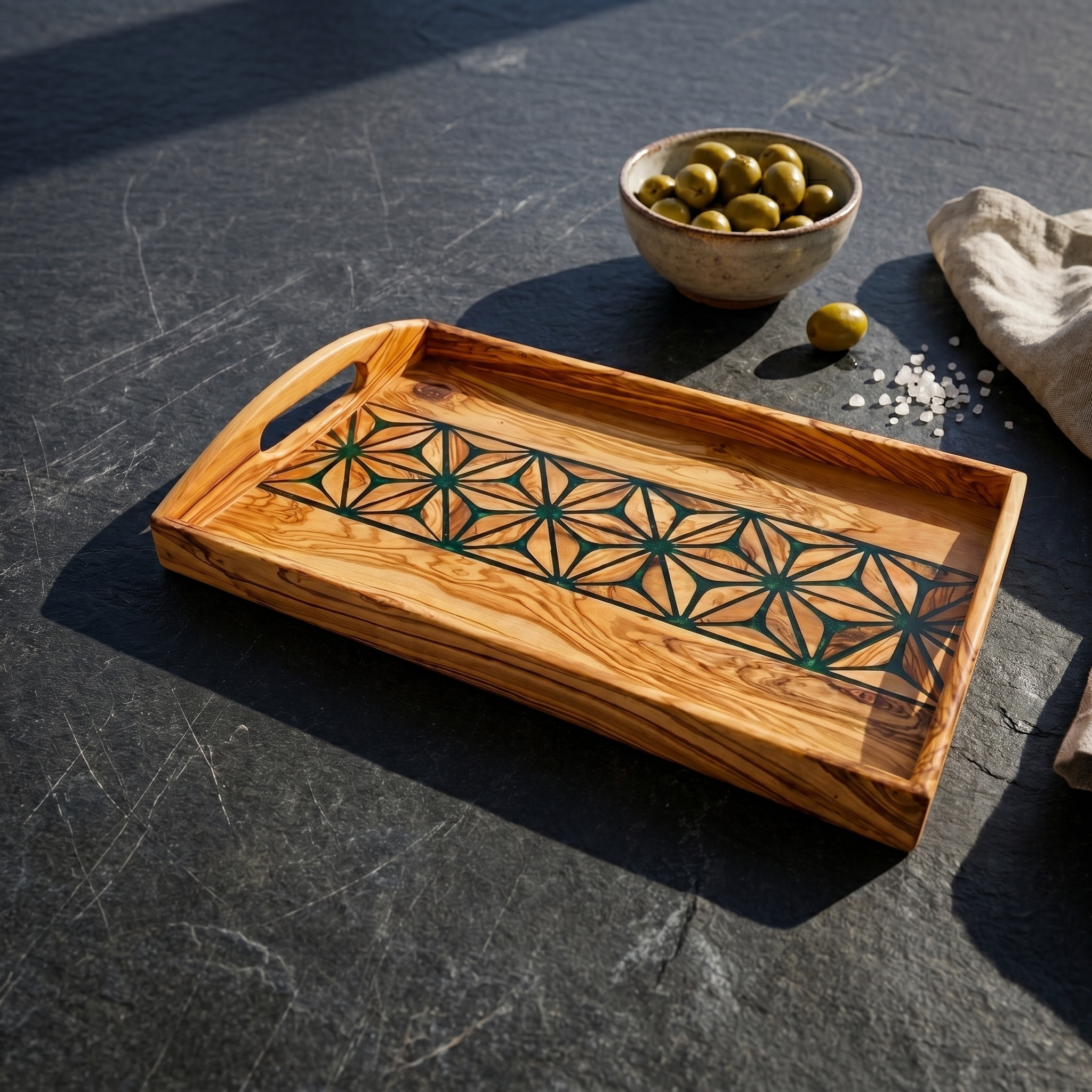 Olive wood serving tray with geometric inlay on a dark stone surface